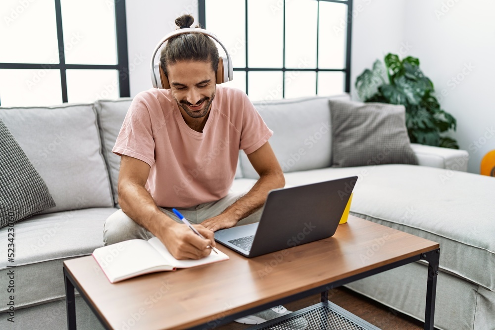 Handsome hispanic man working with laptop sitting on the sofa at the living room at home Handsome hispanic man working with laptop sitting on the sofa at the living room at home