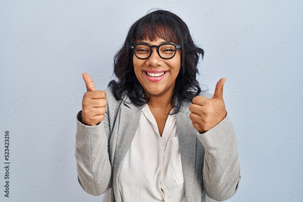 Hispanic woman standing over isolated background success sign doing positive gesture with hand, thumbs up smiling and happy. cheerful expression and winner gesture. Hispanic woman standing over isolated background success sign doing positive gesture with hand, thumbs up smiling and happy. cheerful expression and winner gesture.