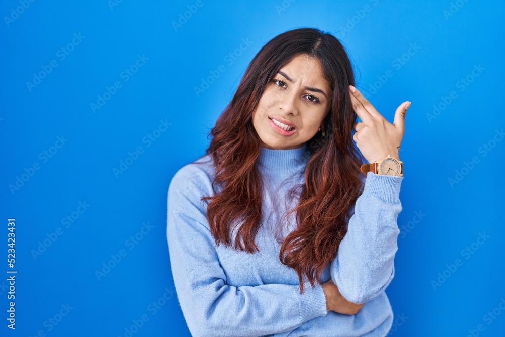 Hispanic young woman standing over blue background shooting and killing oneself pointing hand and fingers to head like gun, suicide gesture. Hispanic young woman standing over blue background shooting and killing oneself pointing hand and fingers to head like gun, suicide gesture.