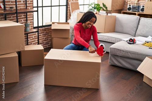African american woman smiling confident packing cardboard box at new home © Krakenimages.com