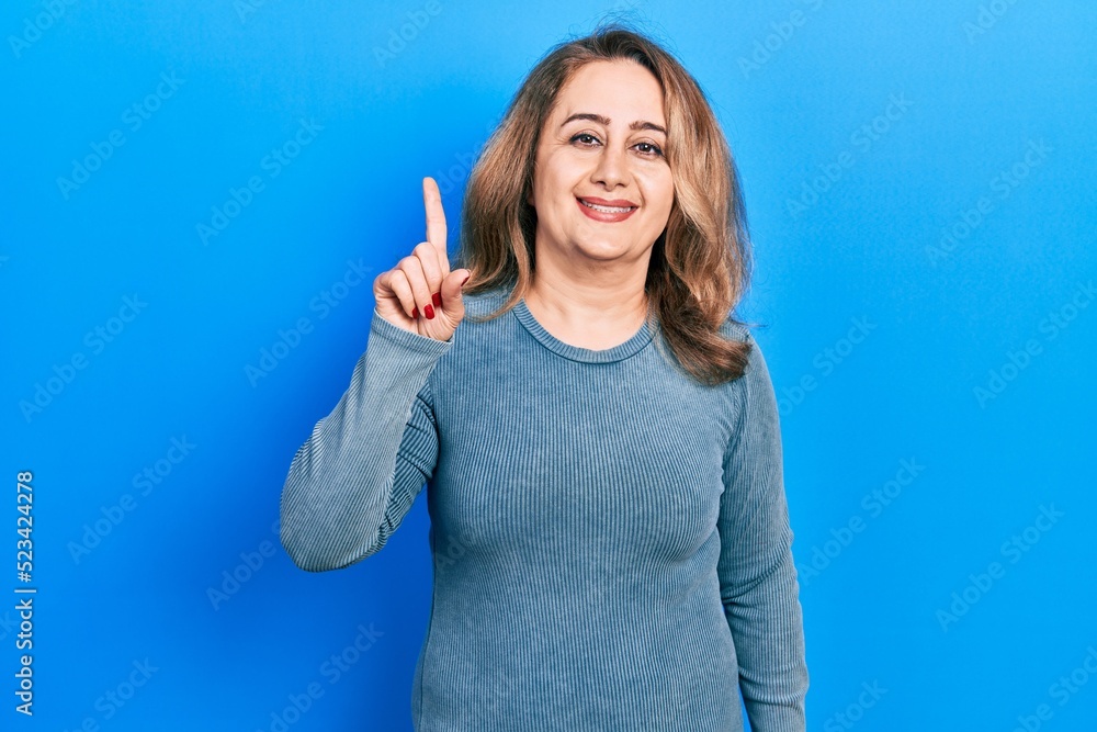 Middle age caucasian woman wearing casual clothes smiling with an idea or question pointing finger up with happy face, number one Middle age caucasian woman wearing casual clothes smiling with an idea or question pointing finger up with happy face, number one