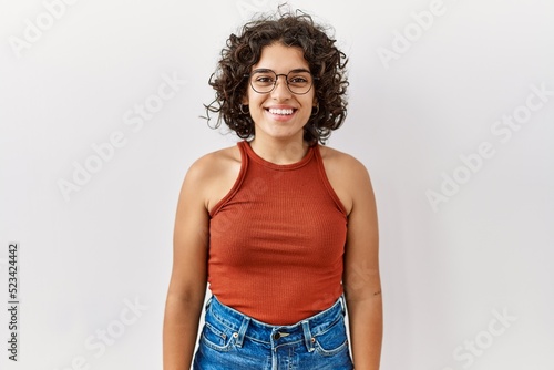 Young hispanic woman wearing glasses standing over isolated background with a happy and cool smile on face. lucky person.