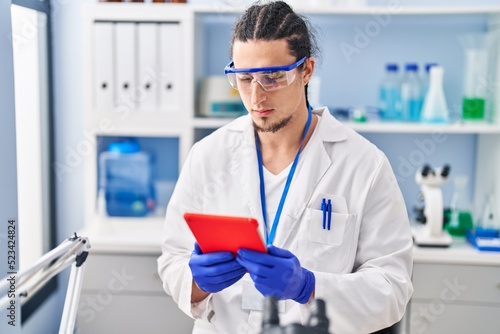 Young man wearing scientist uniform using touchpad at laboratory
