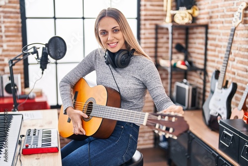 Young woman artist singing song playing classical guitar at music studio