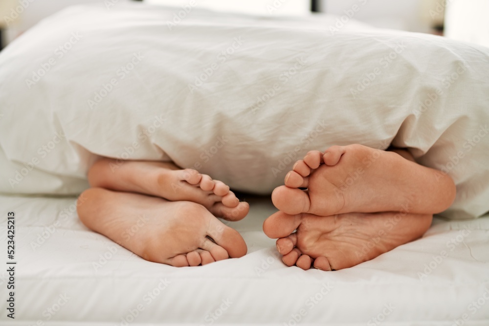 Couple feet under sheets on the bed at home. Couple feet under sheets on the bed at home.