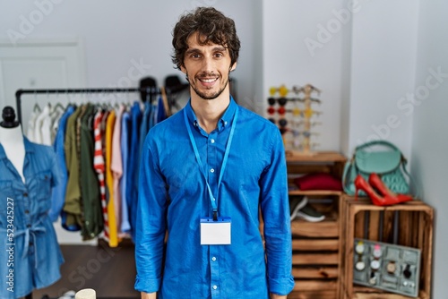 Young hispanic man working as manager at retail boutique with a happy and cool smile on face. lucky person.