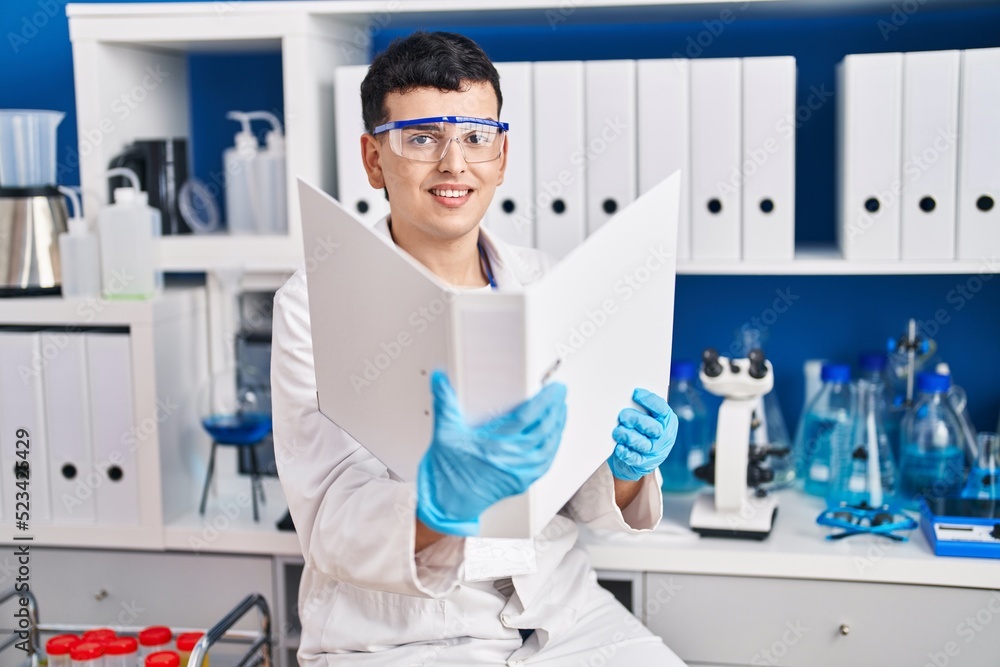 Young non binary man scientist smiling confident reading document at laboratory Young non binary man scientist smiling confident reading document at laboratory