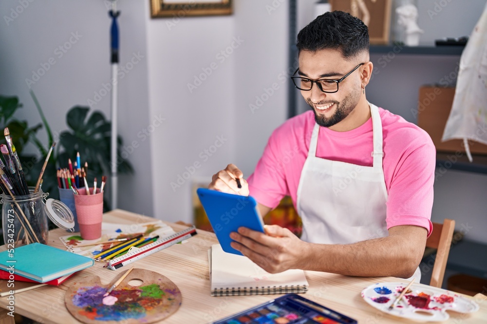 Young arab man artist drawing on notebook using touchpad at art studio