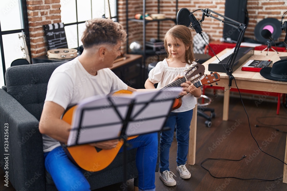 Father and daughter playing classical guitar and ukulele at music studio