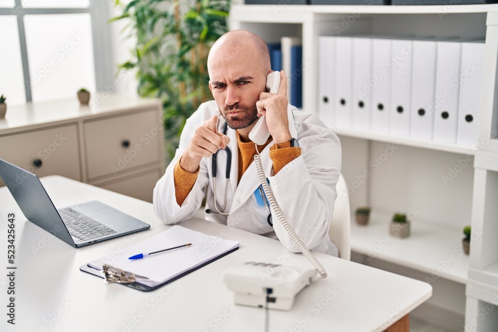 Young bald man with beard working on telephone appointment pointing with finger to the camera and to you, confident gesture looking serious Young bald man with beard working on telephone appointment pointing with finger to the camera and to you, confident gesture looking serious