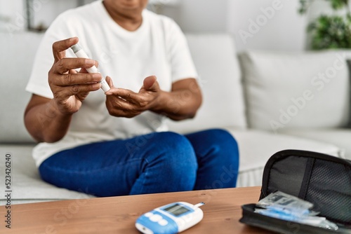 Senior african american woman measuring glucose at home