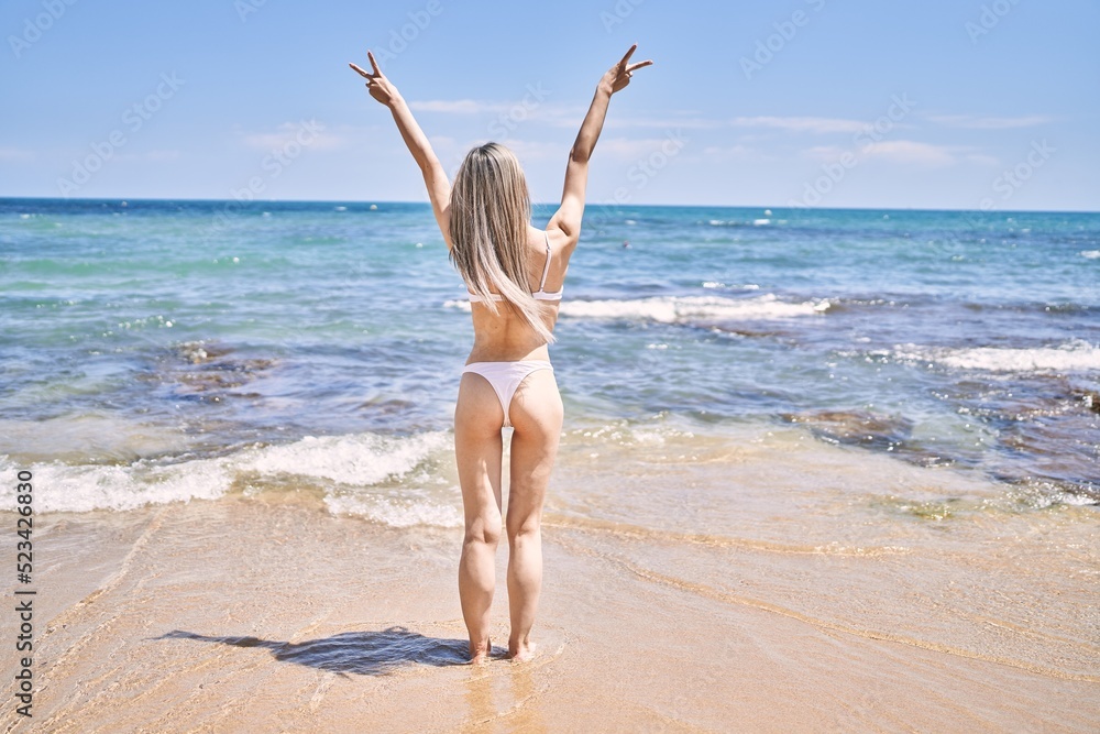 Young chinese girl on back view wearing bikini standing at the beach.