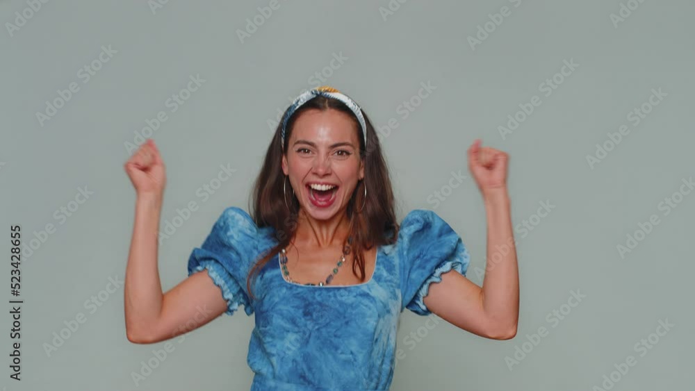 Happy pretty young woman shouting, raising fists in gesture I did it, celebrating success, winning, birthday, lottery goal achievemen. Adult stylish girl isolated on gray studio background indoors Happy pretty young woman shouting, raising fists in gesture I did it, celebrating success, winning, birthday, lottery goal achievemen. Adult stylish girl isolated on gray studio background indoors
