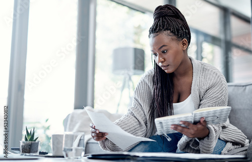 Planning finance, budget and savings with paperwork, bank document and investment report in home living room. Serious, thinking woman reading student loan information and calculating financial future photo