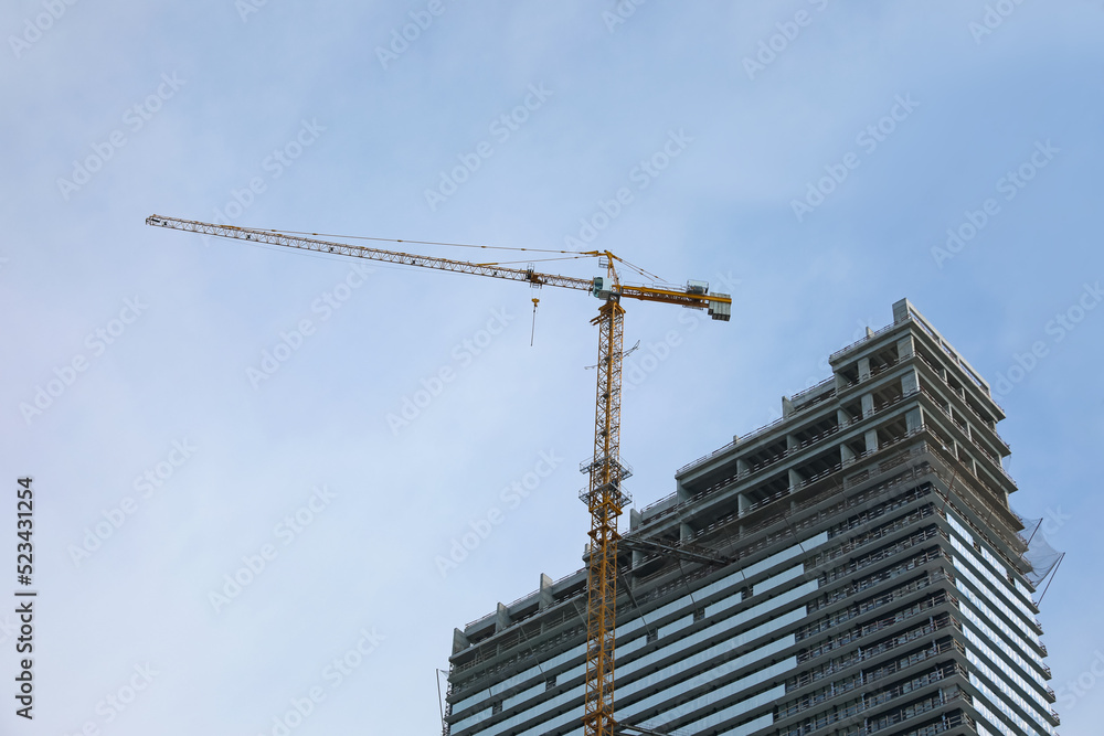 Construction site with tower crane near unfinished building, low angle view Construction site with tower crane near unfinished building, low angle view