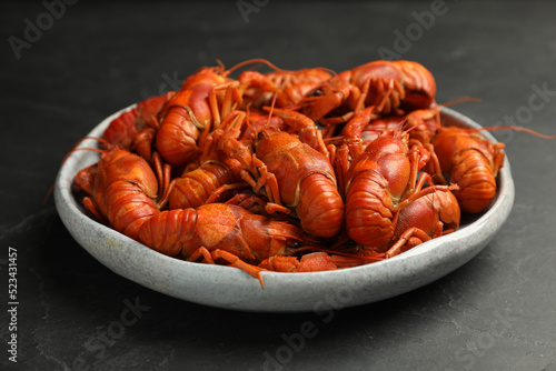Delicious boiled crayfishes in plate on black table