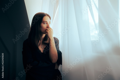 Depressed Sorrowful Woman Looking out the Window. Unhappy person mourning and grieving from recent trauma
 photo