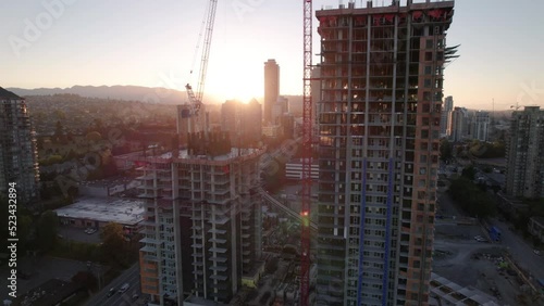 Aerial drone footage sunrise apartment buildings and crane at construction site, sunrise skyscrapers, condominiums, real estate market Vancouver, Brentwood. 4K 4096X2304 24FPS PRORES 422