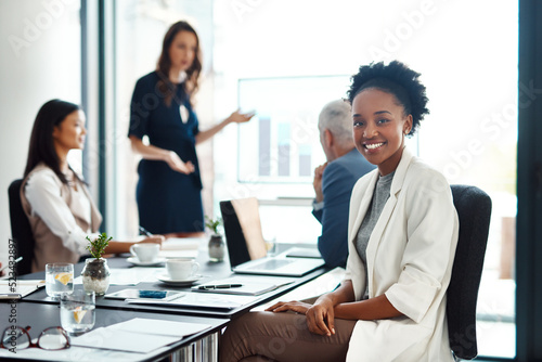 Happy assistant or intern looking cheerful in a team planning meeting at work. Portrait of a proud employee with colleagues as they discuss new innovative plans and strategy in a corporate office photo