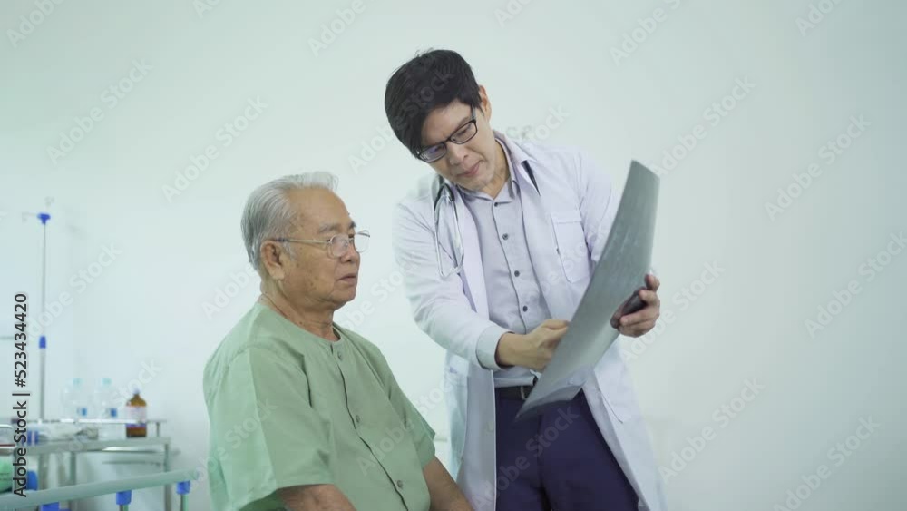 Portrait of Asian doctor showing bone x-ray scan film of sick old senior elderly patient on bed in hospital in medical and healthcare treatment at nursing home. People lifestyle Portrait of Asian doctor showing bone x-ray scan film of sick old senior elderly patient on bed in hospital in medical and healthcare treatment at nursing home. People lifestyle