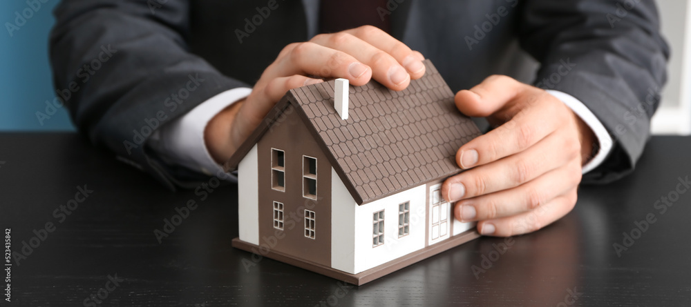 Real estate agent with model of house at table, closeup Real estate agent with model of house at table, closeup