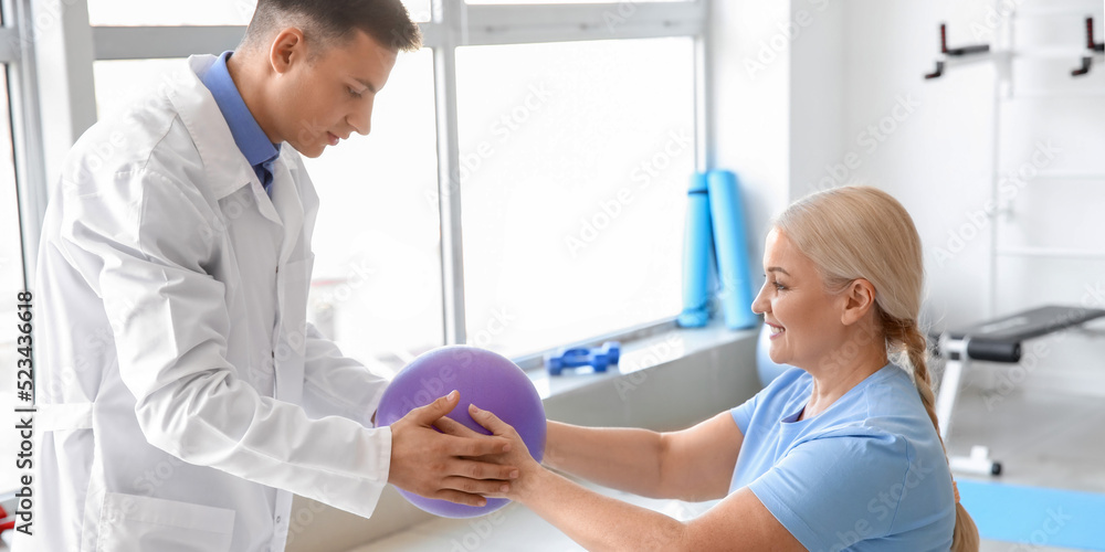 Fototapeta premium Physiotherapist working with mature patient in rehabilitation center