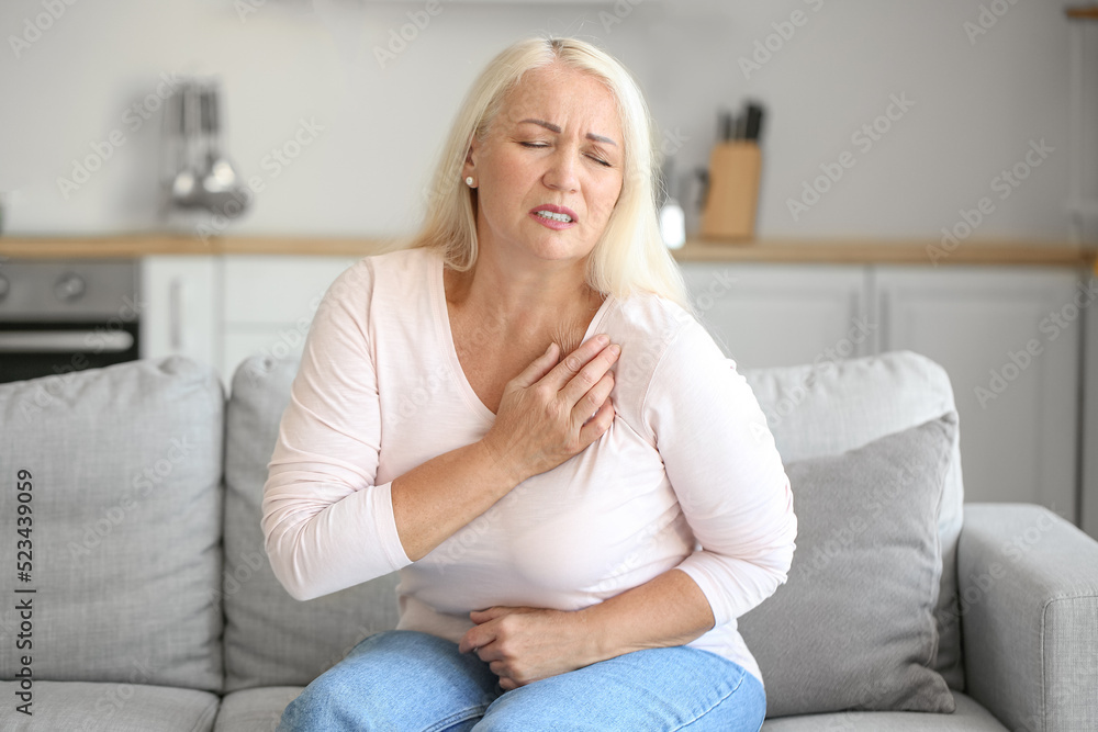 Mature woman suffering from breast pain in kitchen Mature woman suffering from breast pain in kitchen