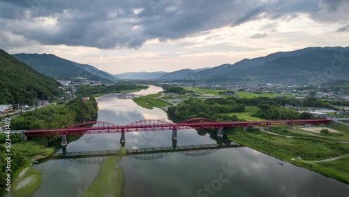 Hyperlapse: Light traffic over arched red bridge over river at dusk