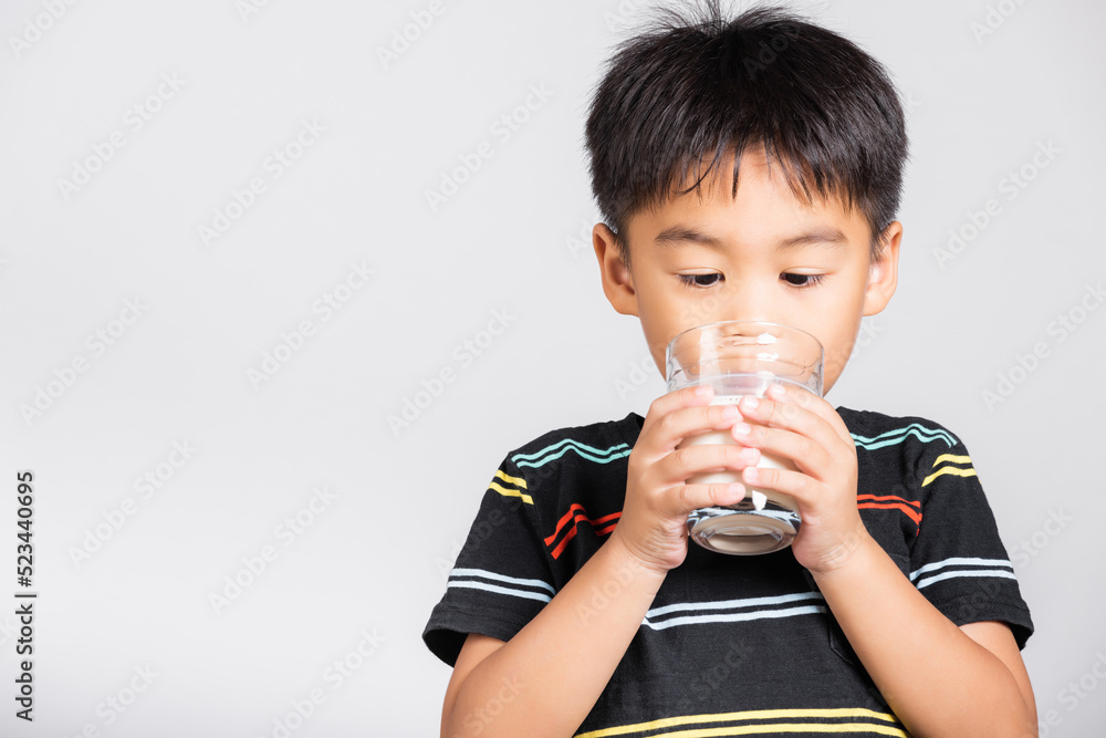 Little cute kid boy 5-6 years old smile drinking fresh water from glass in studio shot isolated on white background, Asian children preschool, Daily life health Little cute kid boy 5-6 years old smile drinking fresh water from glass in studio shot isolated on white background, Asian children preschool, Daily life health