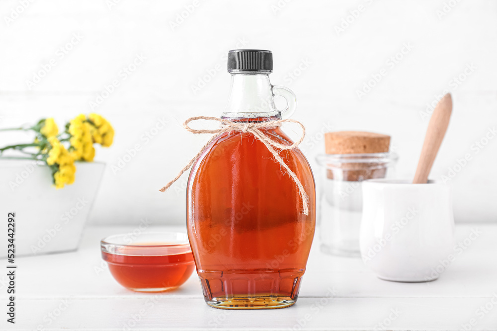 Glass bottle of maple syrup on light background - obrazy, fototapety, plakaty 