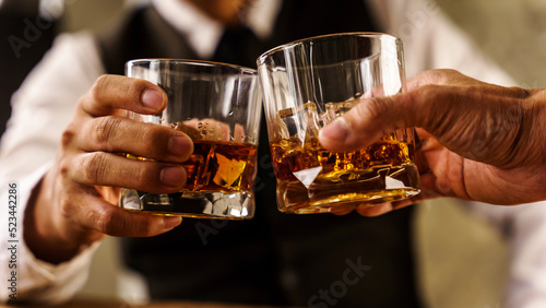 Photography Two hands clink glasses of whiskey wiskey on the couch, cozy