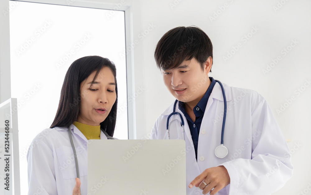 Two professional asian man and woman doctor discussing on laptop to analyse patient person. Two professional asian man and woman doctor discussing on laptop to analyse patient person.