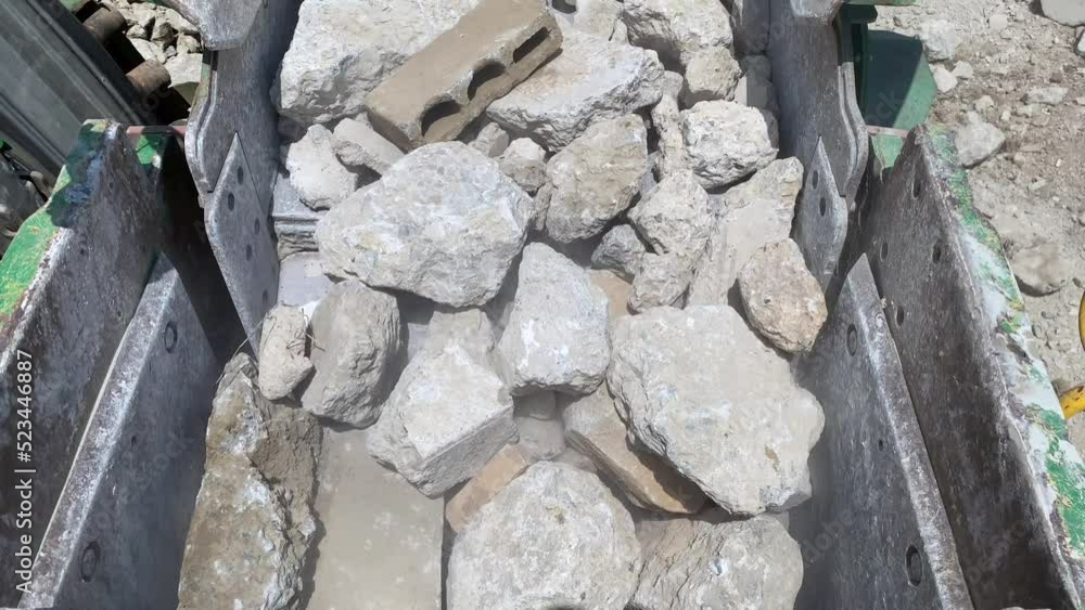 Rocks and concrete being fed into the jaws of a big rock crusher. Rocks and concrete being fed into the jaws of a big rock crusher.