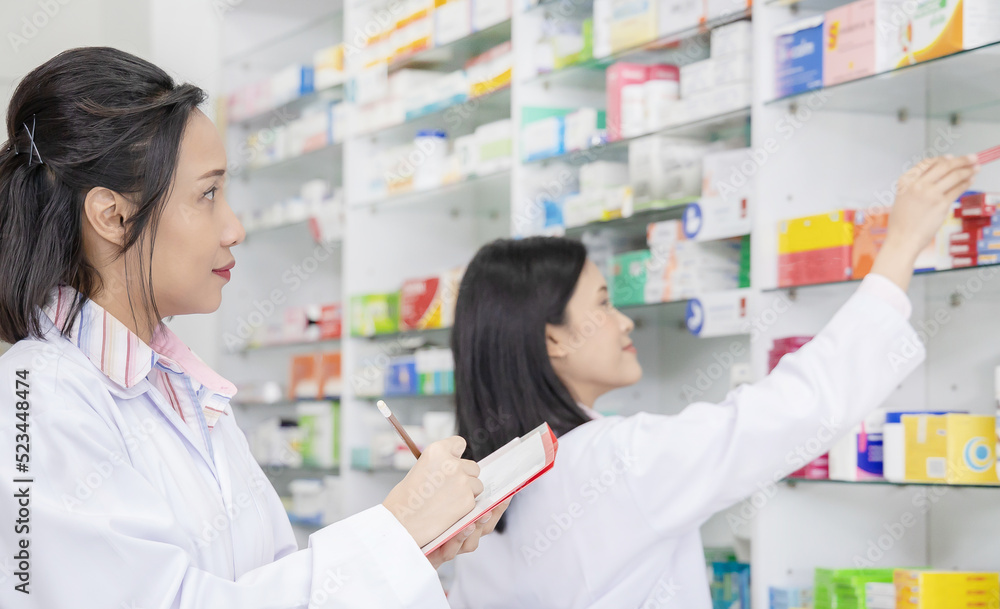 two asian pharmacist chemist women working in pharmacy drugstore