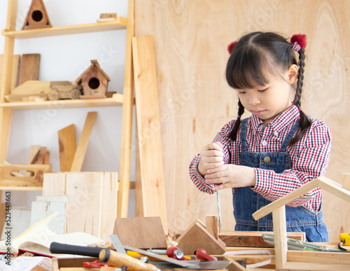 Little asian kid girl works in home carpentry shop.learning concept