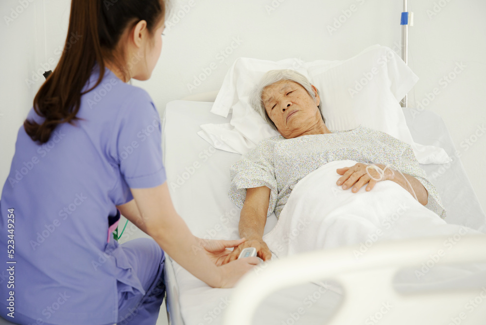 Obraz premium Nurse uses pulse oximeter to measure elderly patient's blood oxygen satuation at home health care