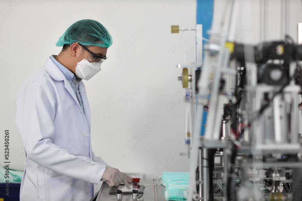 Worker in personal protective equipment or PPE inspecting quality of mask and medical face mask production line in factory, manufacturing industry and factory concept. Worker in personal protective equipment or PPE inspecting quality of mask and medical face mask production line in factory, manufacturing industry and factory concept.