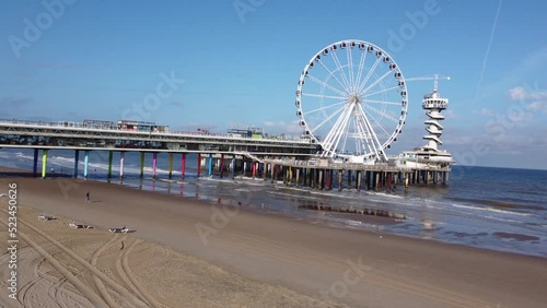 A drone shot of a ferris wheel on the beach. A colourful boulevard walk leads to the ferris wheel and bungy jump point with a deep blue sea in the background photo