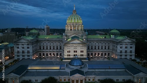 Rising aerial of PA State government building. Harrisburg capitol dome, Susquehanna River at night. Dramatic shot with lights in evening. photo