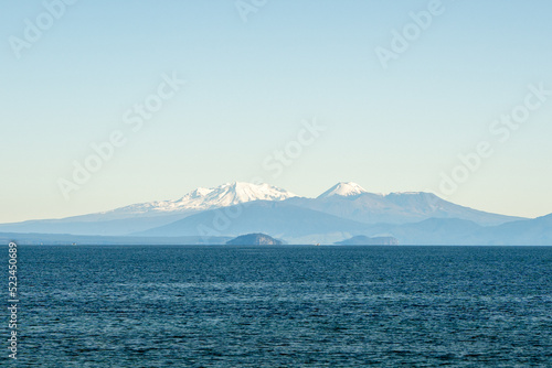 Stand up paddle boarder on Lake Taupo with snow capped mountains in the background