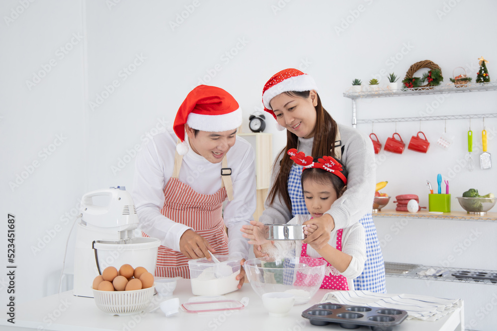 Happy asian family baking cooking cake together in kitchen on Christmas Day