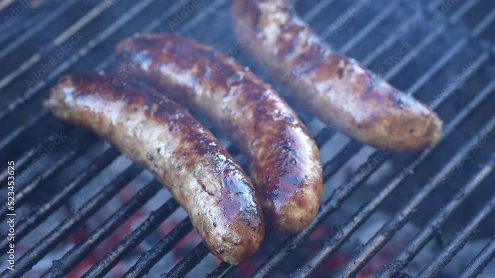 Bratwurst sausage hot dogs smoking and sizzling on the backyard grill Bratwurst sausage hot dogs smoking and sizzling on the backyard grill