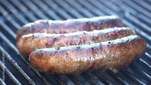 Three bratwurst sausages smoking hot on the grill - isolated close up photo