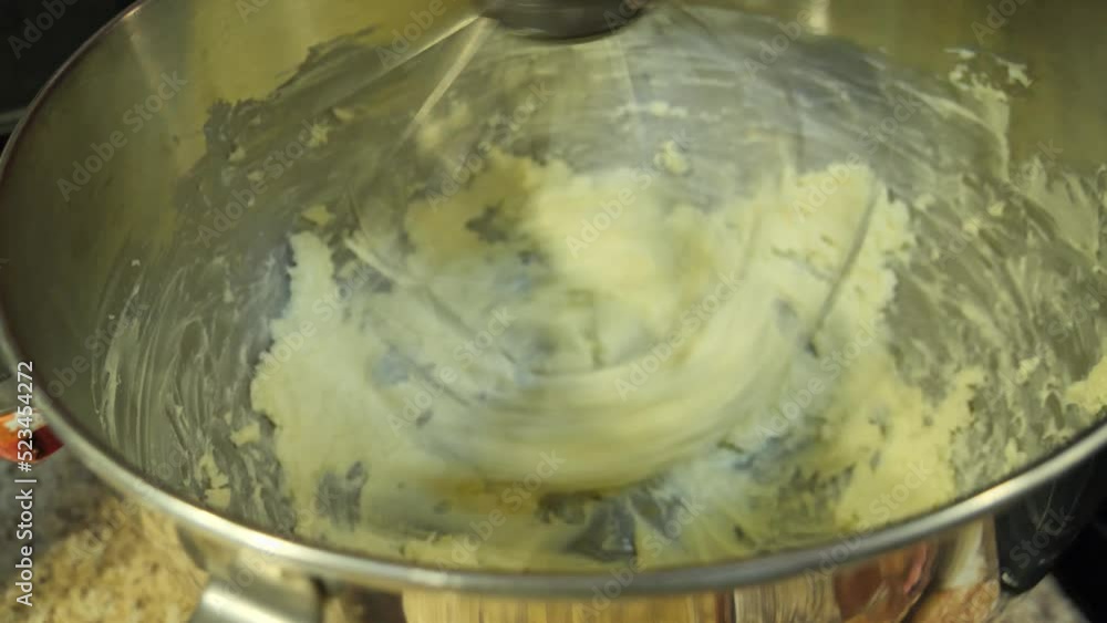 Handheld shot of butter being whipped in a stand mixer Handheld shot of butter being whipped in a stand mixer