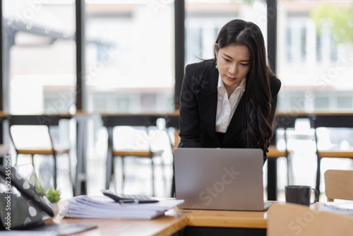 Business Asian woman working with laptop computer and calculator document on an office desk, doing planning analyzing the financial report, business plan investment, finance analysis concept. 