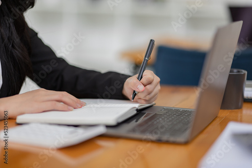Business Asian woman working with laptop computer and calculator document on an office desk, doing planning analyzing the financial report, business plan investment, finance analysis concept. 