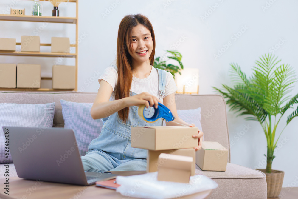 Online trader concept, Female entrepreneur is packing products and sealing parcel boxes with tape Online trader concept, Female entrepreneur is packing products and sealing parcel boxes with tape