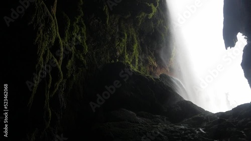 Hideout inside cavern behind waterfall. Gloomy landscape. Rock covered on lichen and moss. Water plunge on opening. Cola de Caballo cataract at Monasterio de Piedra waterfall photo