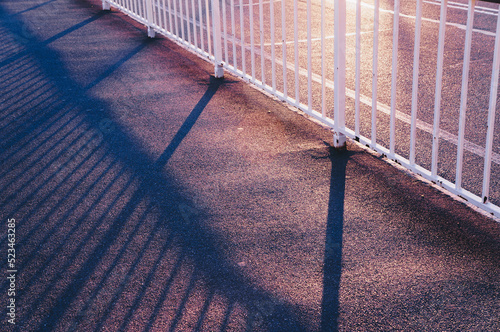 white fence on the edge of the road with sun streaks during sunset