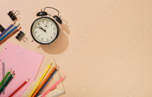 Ready to go back to school, school subjects on a light flesh-colored background. Notepads, pens, pencils, alarm clock and other tools. Banner with place for text.